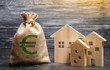 A bag with euro money and three houses. Affordable cheap loan, mortgage. Taxes, rental income. Building houses. Municipal budget of the community. Concept of real estate acquisition and investment.