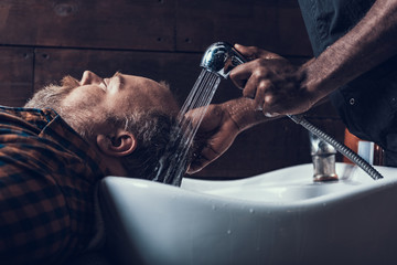 Wall Mural - Hairstylist using shower to washing visitor head