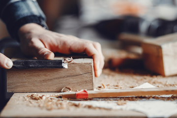 A man carves a tree. The carpenter works in a studio. An engineer provides a tree shape