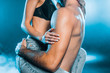 cropped view of man hugging sensual girl on blue smoky background