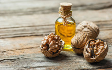 Walnut Oil In Glass Of Bottle, Whole Big Peeled Walnut Kernel With Thin Shell On Wooden Background. Healthy Food For Brain. Fresh Walnuts  Background Nut Concept