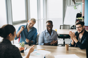 Wall Mural - Colleagues rejoice in success in their business affairs, sitting at the table in their office