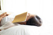 © DG PhotoStock - Women sleeping with a book after tired in study for a long time.