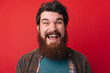 © Vulp - Portrait of an excited bearded man with open mouth isolated over red background