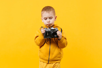 Wall Mural - Little kid boy 3-4 years old wearing yellow clothes hold camera isolated on orange wall background, children studio portrait. People sincere emotions, childhood lifestyle concept. Mock up copy space.