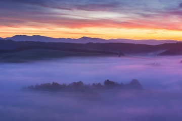 Wall Mural - sunset over misty landscape scenic view of foggy morning sky with rising sun above dreamy forest. mo