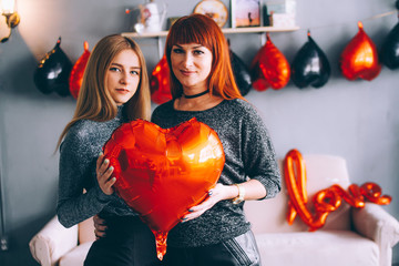 Mom and daughter are holding a red heart