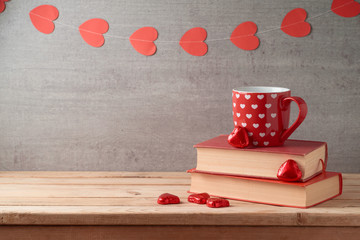 Valentine's day background with coffee cup, books, heart shape chocolate and garland on wooden table