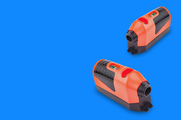 Pair of red and black plastic laser levels with water bubble for horizontal or vertical measure on blue background with copy space for your text. Building or repair concept