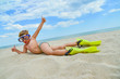 © andov - A cheerful and funny boy in flippers and a mask for scuba diving lies on the sand by the sea and sunbathes in the sun in a clear summer.