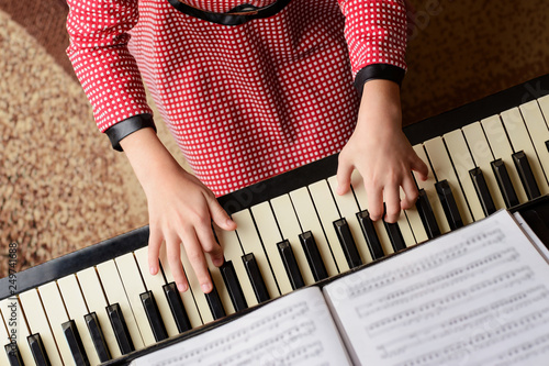 Little girl in red dress performing classical music at home playing the piano lo Tablou Canvas