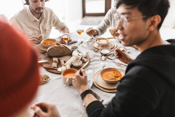 Close up photo of tabale full of food. Group of international friends having lunch spending time together in cafe