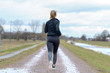 Fit muscular woman jogging away from camera