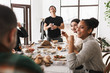 © Anton - Young laughing asian man in eyeglasses and black T-shirt happily holding glass of wine in hand. Group of attractive international friends joyfully spending time together on lunch in cafe