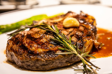 Wall Mural - A sprig of rosemary on a fresh roasted bone-in ribeye steak with garlic, gravy and asparagus