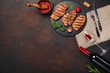 Grilled pork steaks on stone with bottle of wine, wine glass, knife and fork on rusty background