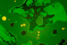 Abstract Background Of A Drop Of Paint On The Water Surface. Green Shades With Yellow Droplets