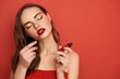 © Yakobchuk Olena - Portrait of attractive girl with closed eyes applying lips on red background