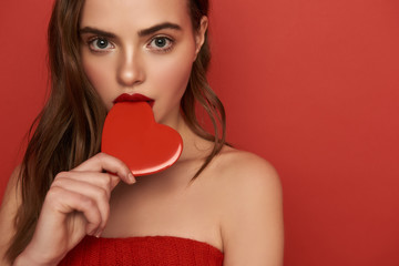 Wall Mural - Cropped photo of young woman touching her lips with decorative heart indoors