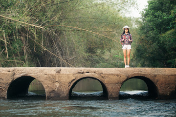 Wall Mural - Backpacker woman standing on old bridge with nature background