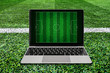 © ParinPIX - Laptop on soccer grass field background.
