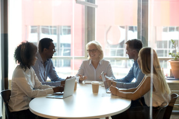 Canvas Print - Five diverse businesspeople sitting in boardroom and negotiating