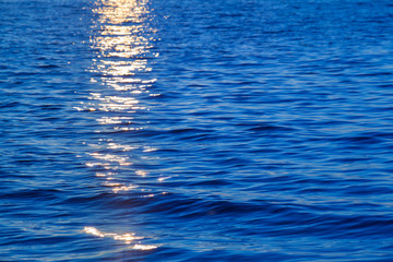 sunset at sea detail / reflecting yellow sunlight at sunset on blue water surface background (copy s