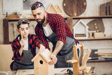 Time For Family. Dad Shows His Little Son How To Make Diy Birdhouse In Wooden Workshop, Using Hand Tools And Wooden Plank