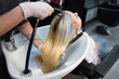 © strigana - Beauty concept - Professional hairdresser applying shampoo, washes color paint off and massaging hair of a customer. Woman having her hair washed in a hairdressing beauty salon