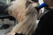 © strigana - Professional hairdresser drying woman's hair with hairdryer in beauty salon