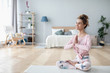 © BestForYou - Time for yoga. Attractive young woman exercising and sitting in yoga lotus position while resting at home.