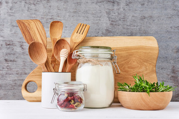 Kitchen background with cutting board wooden utensils and rosemary on a white table