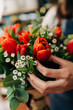 Woman florist makes a orange tulips bouquet on wooden table