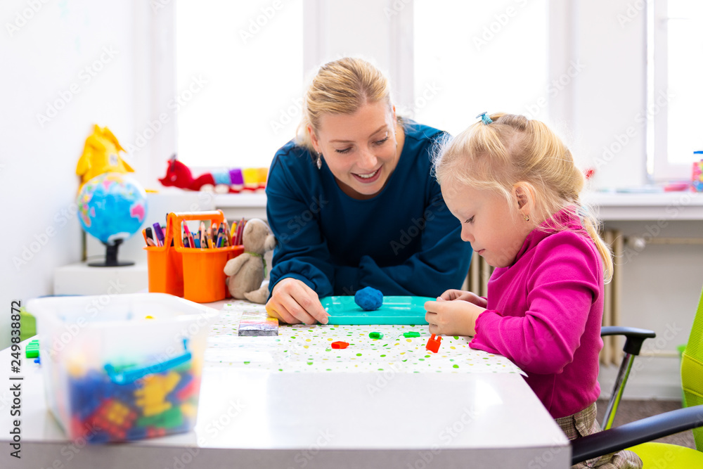 Toddler girl in child occupational therapy session doing sensory playful exercises with her therapist. - obrazy, fototapety, plakaty 