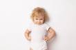 Caucasian curly baby girl in a white T-shirt on a white background hands holding a waist. child hands in hips