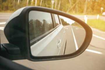 Speed car driving, view from the mirror on an empty highway, motion blur.