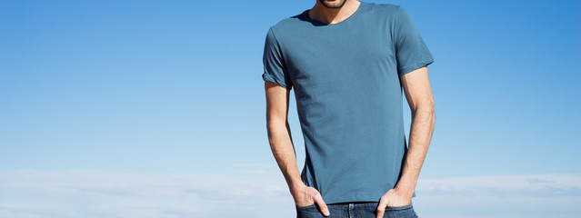 Photo of a man wearing blue t-shirt. Blue sky on background