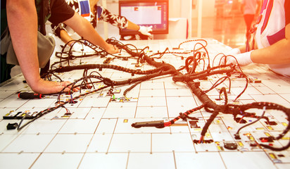 Wall Mural - Hands of employees who check the quality of the wiring for cars at a modern plant on a special stand at the production shop