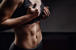 Closeup of drop of sweat on skin abdomen woman after workout. Dark background. Copy space