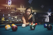 © RomanR - Young and beautiful woman in pub playing billiard