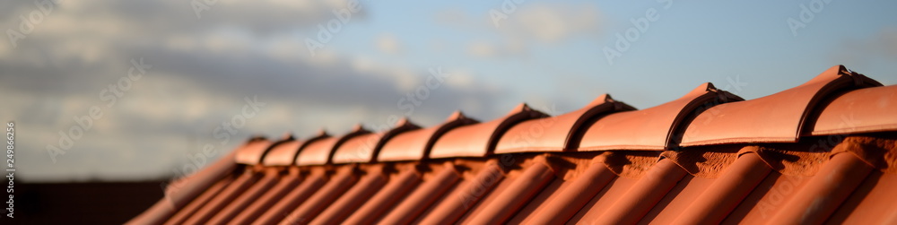 glänzend rote Dachziegel Pfanne vom Dachdecker Handwerker im Sonnenschein vor dunklem Hintergrund - obrazy, fototapety, plakaty 