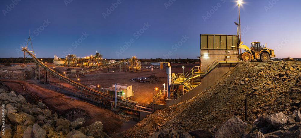 Bulldozer loading rocks into the crusher within the copper mine head at dusk in NSW Australia - obrazy, fototapety, plakaty 