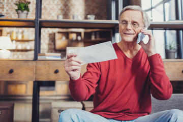 Wall Mural - Cheerful pensioner smiling while making a call to a bank