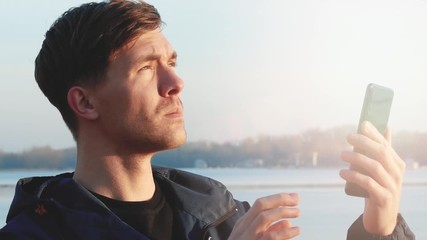 Portrait of young man in sportswear trying to catch a cellular signal. Close up