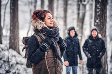 Portrait Of A Beautiful Redhead Girl With A Backpack Walking With His Friends Through A Winter Woods
