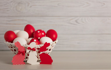 Happy Easter! Painted Easter eggs and Easter decoration - Easter bunnies with ribbons - red, white and red with white polka dots on a gray wooden background.