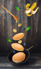 Wall Mural - Pancakes, blueberries and banana flying into iron skillet