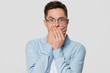 © fizkes - Shocked scared man with surprised face covering mouth with hands