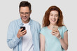 © fizkes - Happy young couple holding phones enjoying chatting in messengers