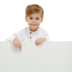 Wall Mural - A little boy is looking from behind an empty banner.